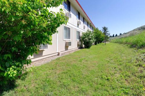 a white building with a grass field next to it at Super 8 by Wyndham Cody in Cody