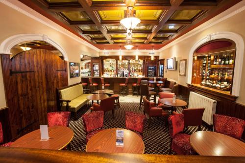 a restaurant with tables and chairs and a bar at Adair Arms Hotel in Ballymena
