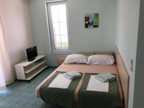 - une chambre avec un lit et des serviettes dans l'établissement Apartments IRENA, à Vodice