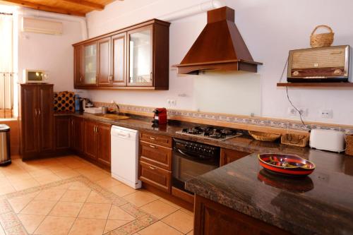a kitchen with wooden cabinets and a stove top oven at Ca Miquelet - Turistrat in Albocácer