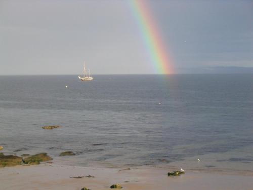 a rainbow over the ocean with a boat in the water at Seascape Largo in Lundin Links