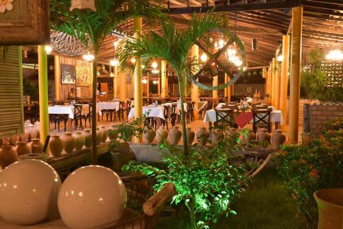 Porto Preguiças Resort في باريرينهاس: مطعم بالطاولات والكراسي والنباتات