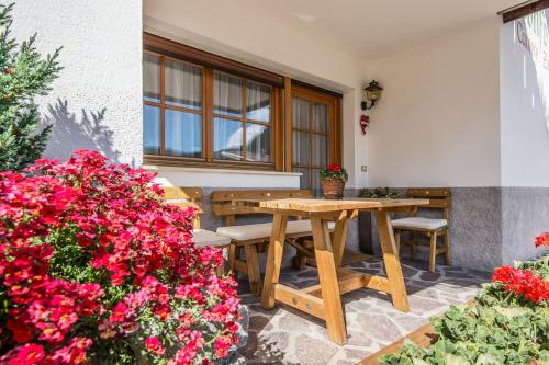 d'une terrasse avec une table en bois et quelques fleurs. dans l'établissement Ciasa Confolia, à Corvara in Badia