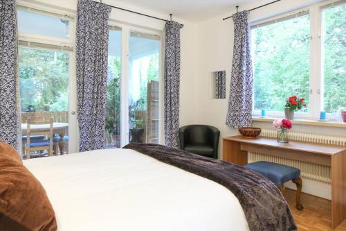 a bedroom with a bed and a desk and windows at White Villa in Baden