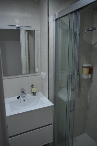 a bathroom with a sink and a glass shower at Apartamento Playa Victoria - Cádiz in Cádiz