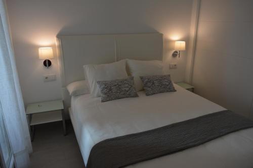 a bedroom with a white bed with two pillows on it at Apartamento Playa Victoria - Cádiz in Cádiz