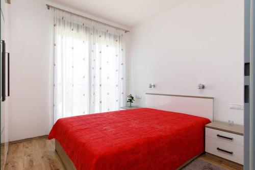 una camera con letto rosso e finestra di APARTMENT RUZA - POOL a Donji Seget