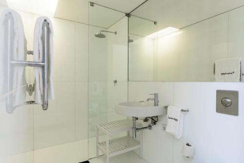 a white bathroom with a sink and a shower at Convento das Bernardas Charming - Tavira in Tavira