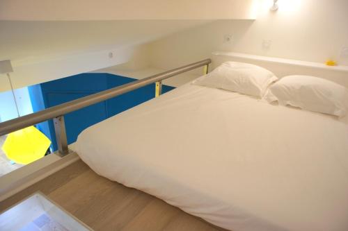 a bed with white sheets and pillows in a room at Ze Perfect Place - Superbe Studio Vieux Nice - calme et climatisé in Nice