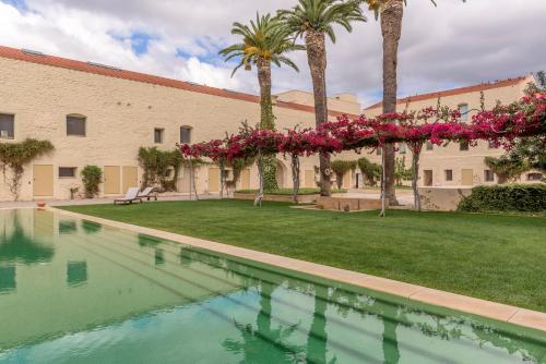 a swimming pool in front of a building with palm trees at Convento das Bernardas Charming - Tavira in Tavira