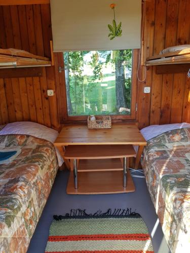 una stanza con due letti e una scrivania in una casetta minuscola di Jaaguranna Lillelaager a Tõstamaa