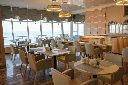 a restaurant with tables and chairs and large windows at Lancaster Eden Bay in Beirut