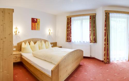 1 dormitorio con 1 cama con sábanas blancas y ventanas en Appartements Michaela, en Neustift im Stubaital