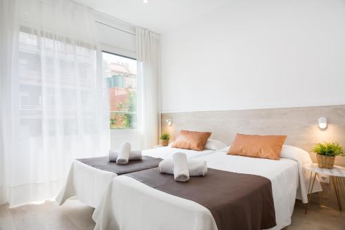 two beds in a white room with a window at BcnStop Sagrada Familia in Barcelona