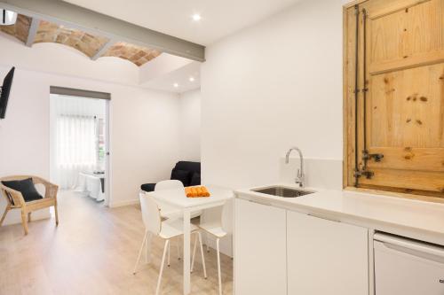 a kitchen with white cabinets and a table and chairs at BcnStop Sagrada Familia in Barcelona