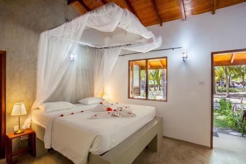 a bedroom with a white bed with a canopy at De Silva Palm Resort in Kalpitiya