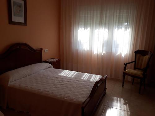 a bedroom with a bed and a chair and a window at O'Corpiño in Muxia