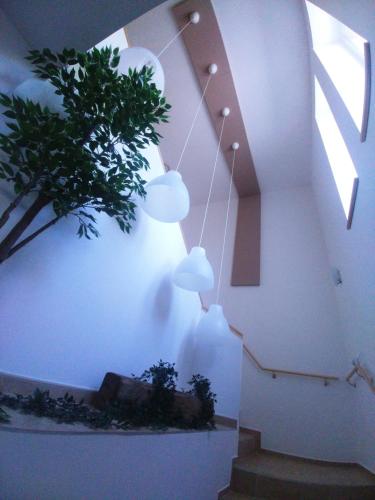 a staircase with pendant lights and a plant on the wall at Sarok Apartmanház in Makó