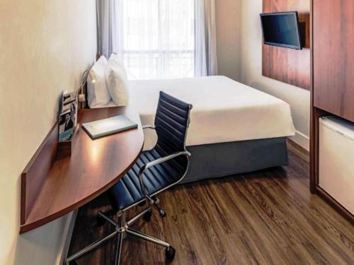 a hotel room with a desk and a bed and a computer at Mercure Sao Caetano do Sul in São Caetano do Sul