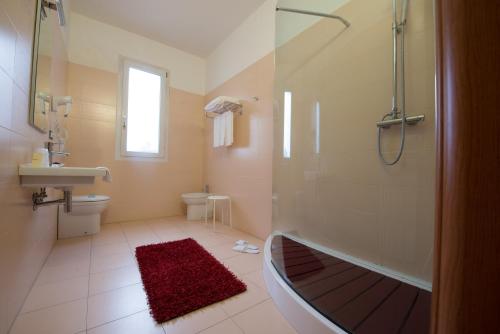 a bathroom with a shower and a tub and a sink at Hotel Formula International in Rosolina