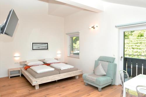 a bedroom with a bed and a chair and a window at Traubenhof in Magrè allʼ Adige