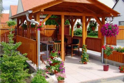 a wooden gazebo with a table and some flowers at Rodinny penzion Kunc in Slavonice