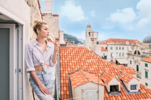 a woman standing on a balcony looking out of a window at Scalini Palace in Dubrovnik
