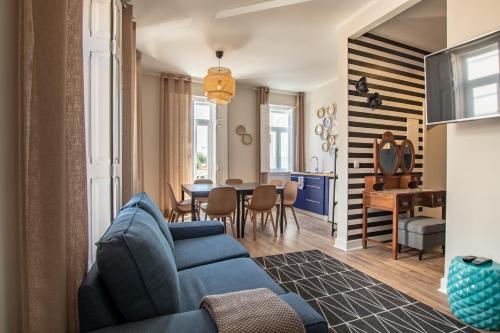 a living room with a blue couch and a dining room at Carnot House in Setúbal