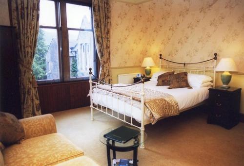 a bedroom with a bed and a chair and a window at Caddon View Country Guest House in Innerleithen