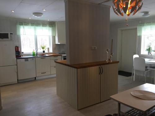 ムーラにあるGamla Landsvägen 3の白いキャビネットとテーブル付きのキッチンが備わります。