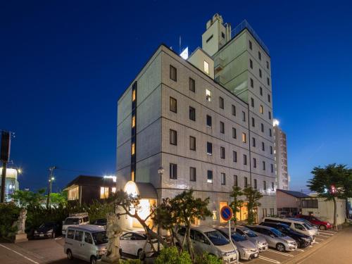 duży budynek z samochodami zaparkowanymi na parkingu w obiekcie APA Hotel Tsubame-Sanjo Ekimae w mieście Tsubame