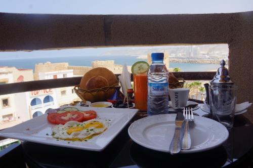a table with a plate of food and a view of the city at Hôtel Riad Asfi in Safi