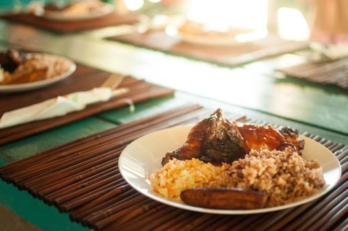a plate of food with meat and rice on a table at Ranguana Caye Cabanas in Placencia Village