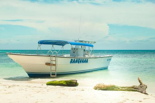 a boat sitting on the beach next to at Ranguana Caye Cabanas in Placencia Village