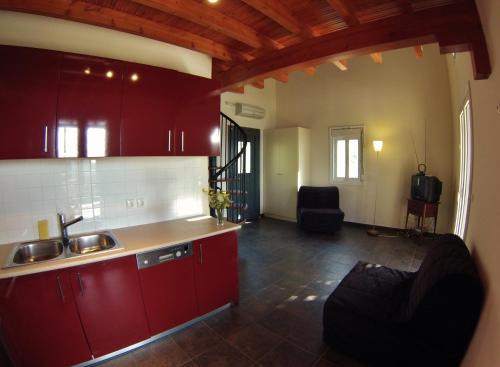 una cucina con armadi rossi e lavandino di Casa Nostos a Vassiliki