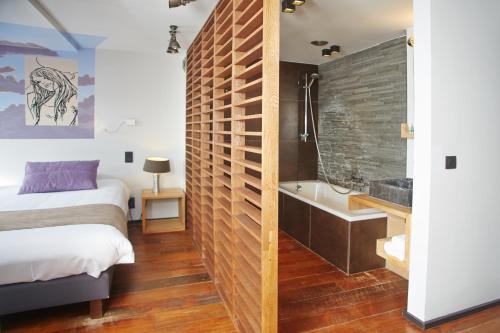 a bedroom with a bed and a bath tub next to a bed at Boutique Hotel Saint-Géry in Brussels