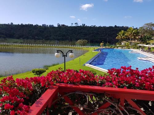 uma piscina com flores vermelhas ao lado de um corpo de água em Cond. Águas da Serra, Bananeiras em Bananeiras