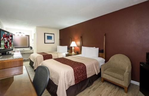 a hotel room with two beds and a chair at Extended Stay - Ormond Beach in Ormond Beach