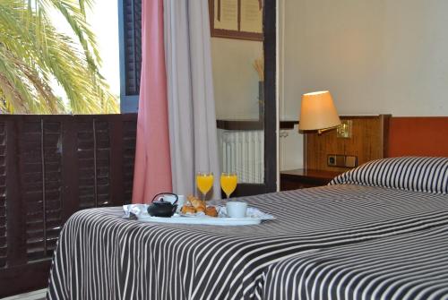 a table with a plate of food and two glasses of orange juice at Hotel El Castell in Sant Boi del Llobregat