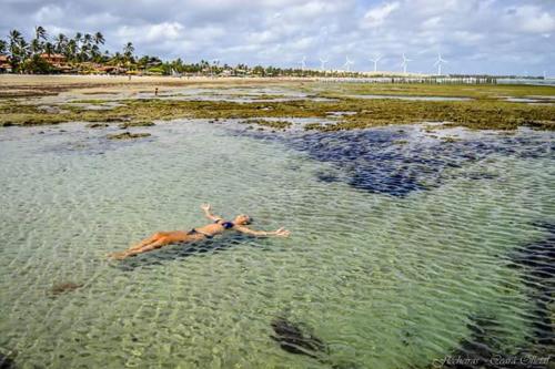 a woman laying in the water on a beach at Pousada Sena in Flecheiras