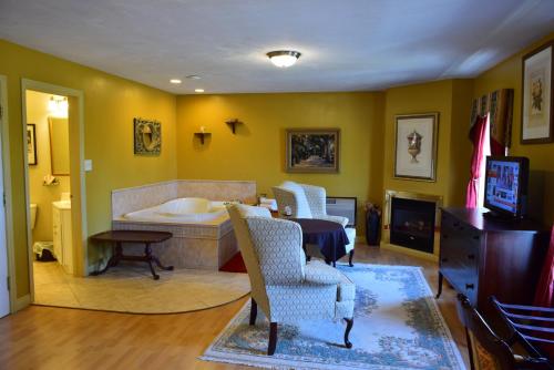a living room with a tub and a table and chairs at Auberge Wild Rose Inn in Moncton