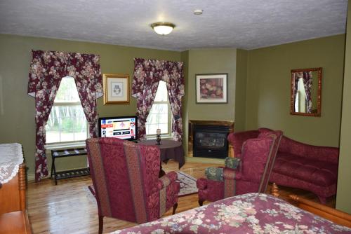 a living room with two chairs and a fireplace at Auberge Wild Rose Inn in Moncton