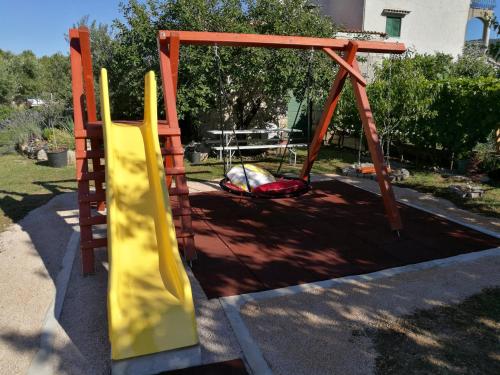 a playground with a slide and a swing set at Guesthouse Villa DomeNico in Lozovac