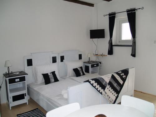 a white bedroom with a white couch and a tv at Pannonia Terranova in Vardarac
