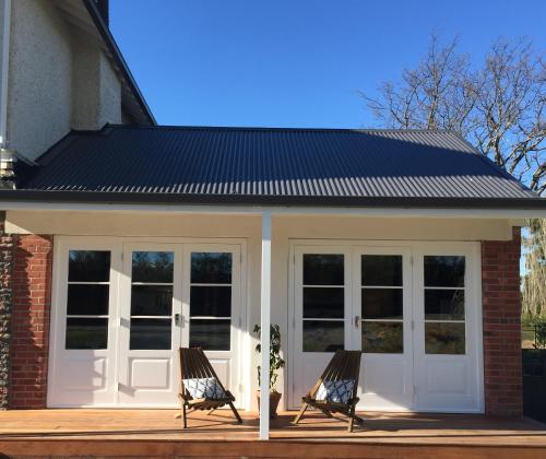 a screened in porch with two chairs on a deck at The Studio at Northfield in Methven