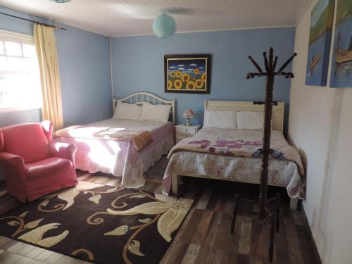 um quarto com uma cama e uma cadeira em Refugio Fofo - casa de temporada em Campos de Jordão