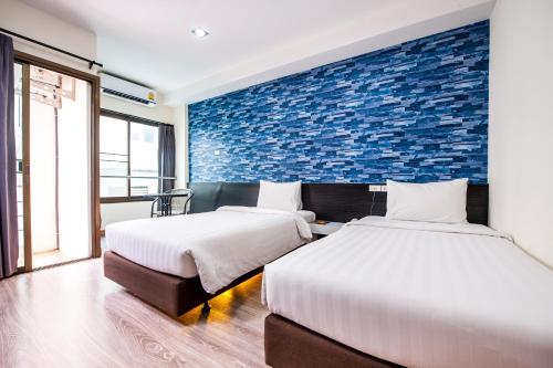 - 2 lits dans une chambre avec un mur en briques dans l'établissement Prajaktra City Hostel, à Udon Thani