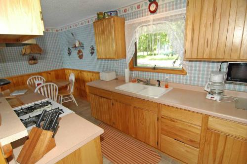 cocina con armarios de madera, fregadero y ventana en Ranch-Style Seidls Home, en Namekagon