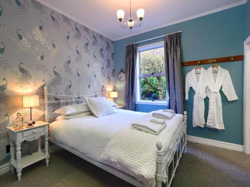 a blue bedroom with a bed and a window at The Ferry Bed & Breakfast in Queenstown