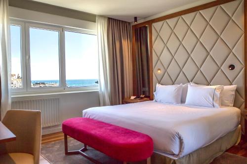 a hotel room with a large bed and a large window at Hotel Silken Palacio Uribarren in Lekeitio